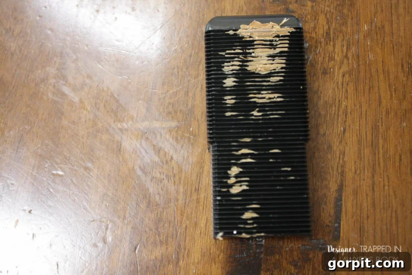Using a plastic leveling tool to smooth excess burn-in stick filler on a table.