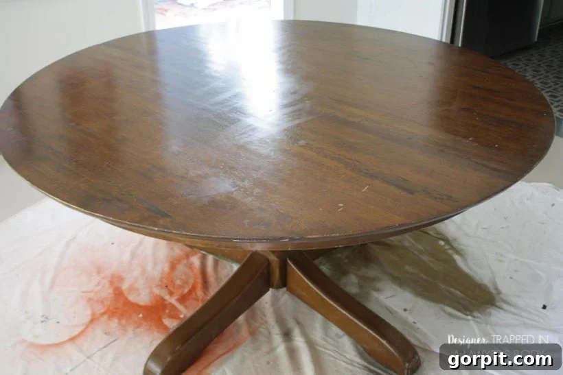 Dining table before refinishing, showing visible wear and scratches on the tabletop.