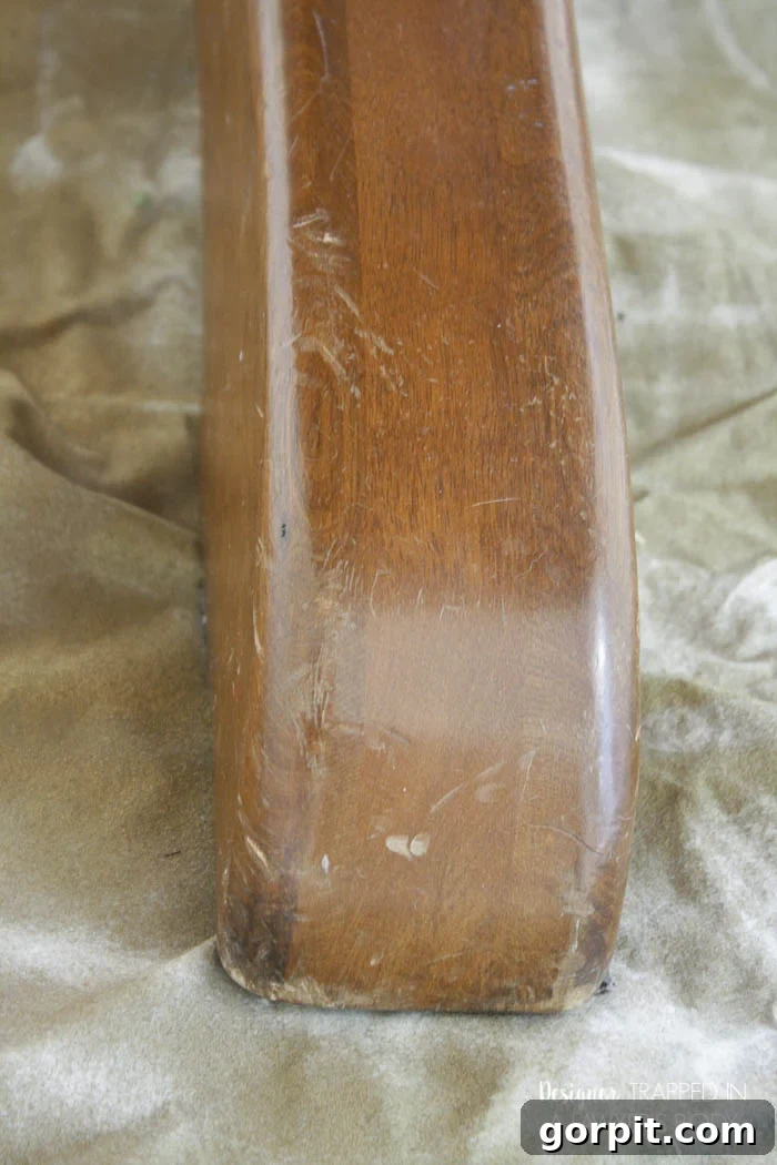 Scratched table legs and base before refinishing, indicating overall wear.