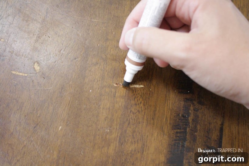 Using a Mohawk Ultra Touch-Up Marker to fill in scratches on a wooden tabletop.