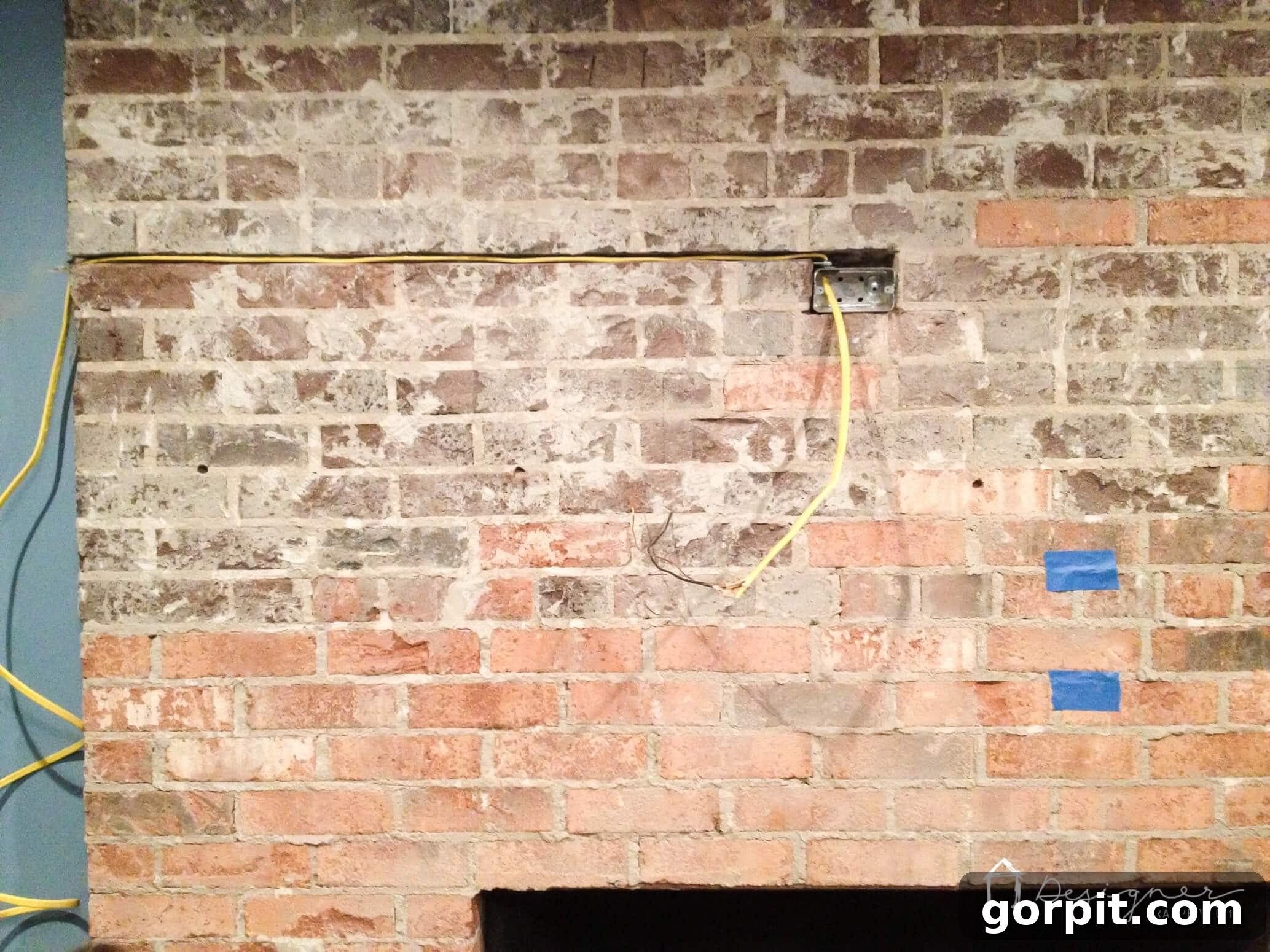Close-up of a channel being carved into brick mortar for hidden electrical wiring during a fireplace renovation.