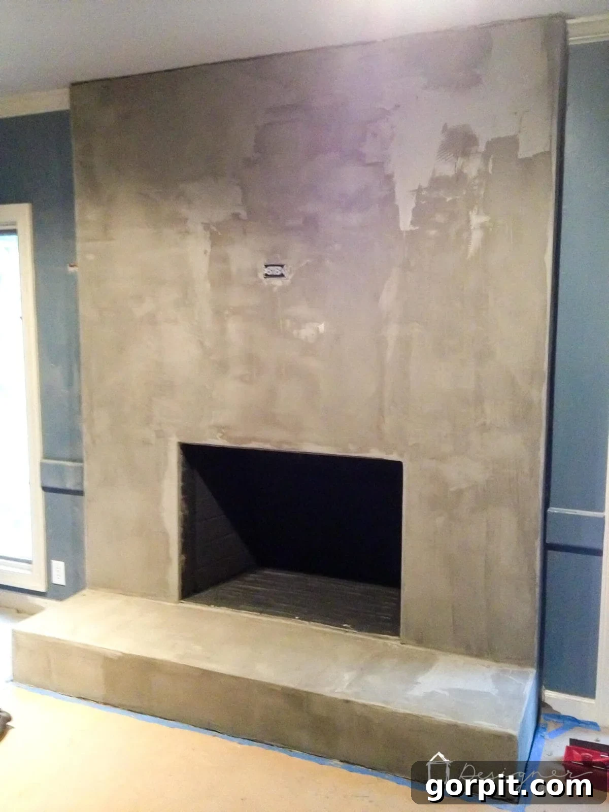 DIY concrete fireplace after several coats, showing how seams have disappeared and a smooth finish is emerging.